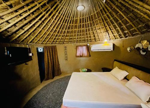 1 dormitorio con cama y techo de paja en The hut house, en Jāmb