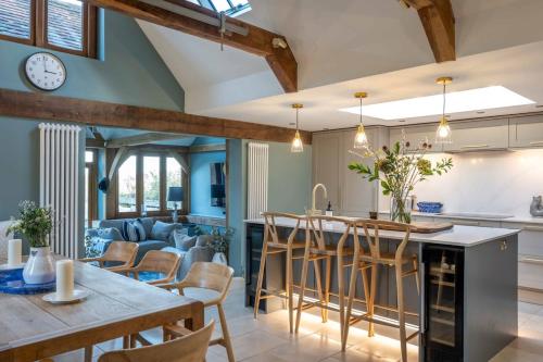a kitchen and living room with blue walls and wooden beams at Super Host Large Luxury Cottage South Downs Park in Lodsworth