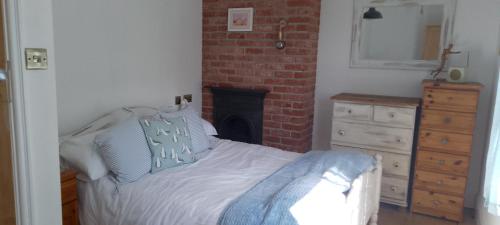 a bedroom with a bed and a brick fireplace at Small cottage in Stratton, Bude in Stratton