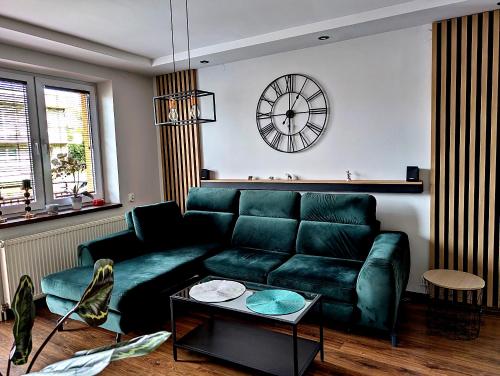 un soggiorno con un divano verde e un orologio di Dom w Kryspinowie a Kryspinow