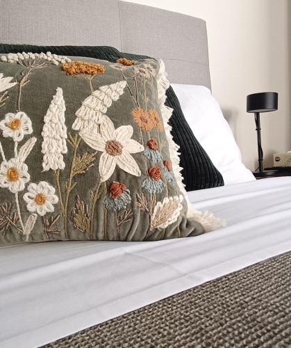 a bed with a pillow with a flower pattern on it at Hahndorf Oak Tree Cottages in Hahndorf