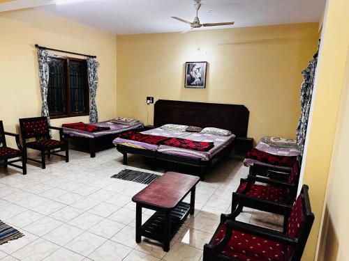 a room with three beds and chairs in it at Aksha Inn in Madikeri