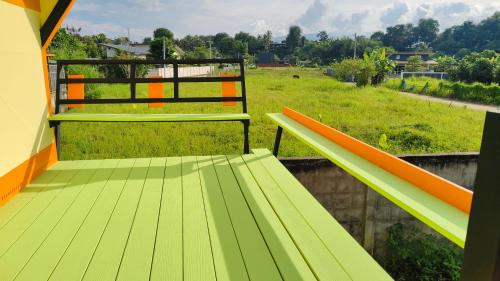 a green and orange bench on a balcony with a field at ทุ่งเศรษฐีโฮมสเตย์แอนด์คาเฟ่ in Chiang Dao