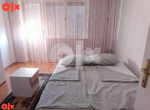 a bedroom with a large bed with a night stand at Apartman Čeliković in Bosanski Šamac