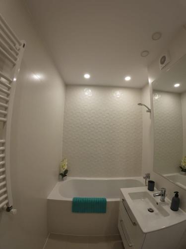 a white bathroom with a tub and a sink at Lovely Sunrise in Bucharest