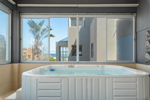 a large white tub in a room with windows at 51 Dolphin Drive in Cape Town
