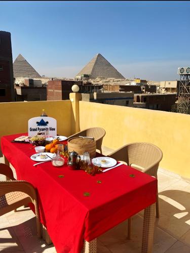 a table with a red table cloth on a balcony with pyramids at Grand Pyramid View Hotel in Cairo