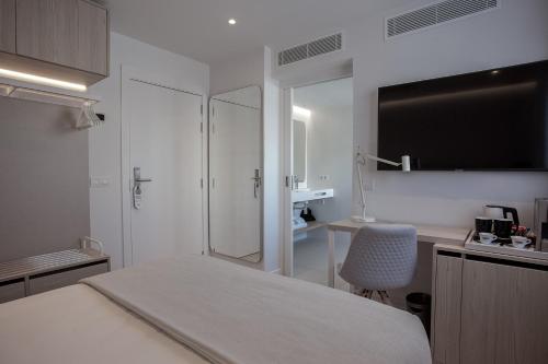 Habitación blanca con cama, escritorio y silla en MIM Mallorca Member of Melia Collection, en Sa Coma