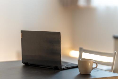 Una computadora portátil sobre una mesa con una taza de café. en Loft Ticinese with Wi-Fi and Netlfix, en Milán