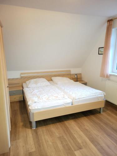 a bed in a bedroom with a wooden floor at Haus Kiki in Dornumersiel