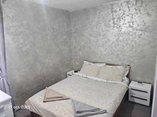 a small bedroom with a bed and a gray wall at Ana in Râmnicu Vâlcea