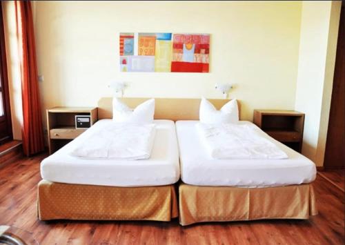 two twin beds in a room with wooden floors at Hotel an der Hörn in Kiel