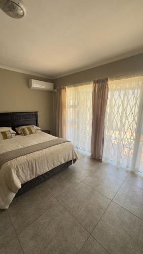 a bedroom with a bed and a window with curtains at Homes by Palesa in Maseru