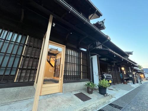 a building with a wooden door on a street at Kominka Hotel Hinataya- Self Check-in System宿場を眺める古民家宿 陽屋 in Nakatsugawa
