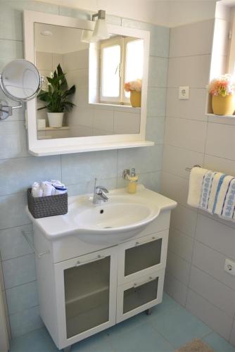 a white bathroom with a sink and a mirror at Beachfront Villa Gradina in Vela Luka