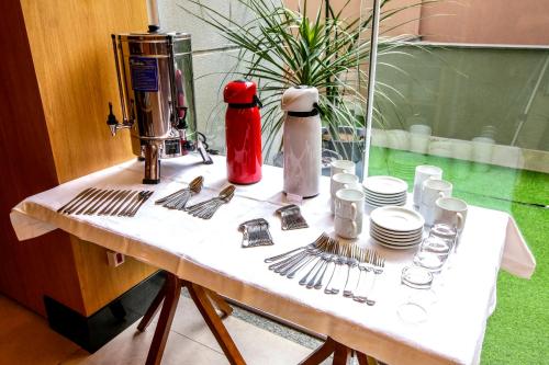 a table with plates and utensils on it at MLG Hotel in Mogi das Cruzes