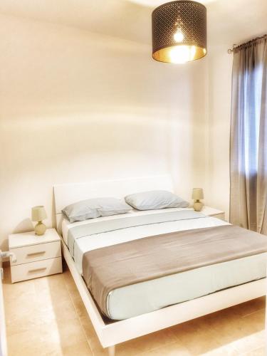 a white bedroom with a bed and a lamp at Residence San Bull in Metaponto