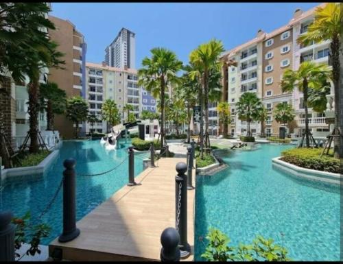 a pool in a resort with palm trees and buildings at Seven seas cote Apartment in Na Jomtien