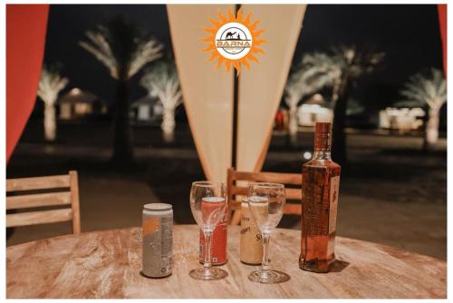 KūriにあるBarna desert camp jaisalmerのグラスとサーフボードとボトルが置かれたテーブル