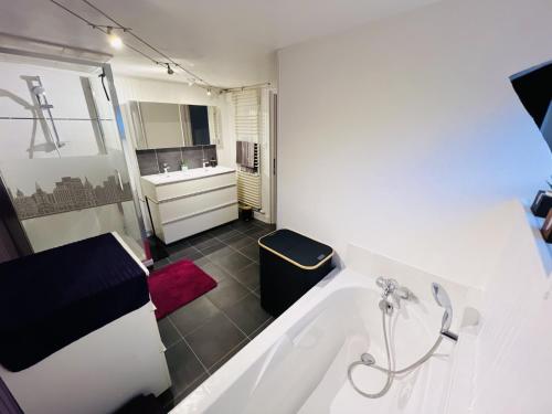 a white bathroom with a tub and a sink at Chez Eliane in Bennwihr