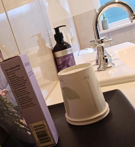 a bottle of soap and a cup next to a sink at Hahndorf Oak Tree Cottages in Hahndorf