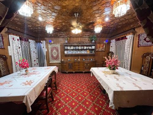 a dining room with two tables with flowers on it at heritage new moon premium houseboat in Srinagar