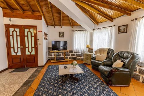 a living room with leather furniture and a tv at Quinta da Espadana in Povoação