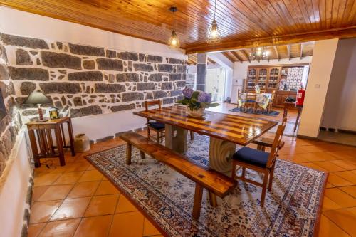 a dining room with a table and a stone wall at Quinta da Espadana in Povoação
