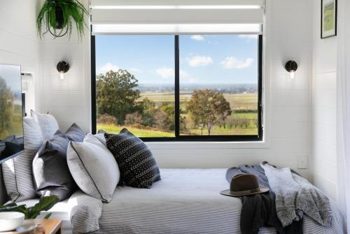 a bedroom with a bed with pillows and a window at The Bunker Malniri Park in Wilberforce