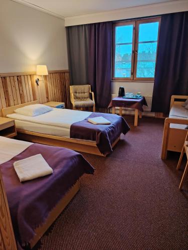 a hotel room with two beds and a chair at Juthbacka Hotell in Uusikaarlepyy