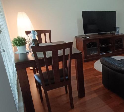 un salon avec une table, des chaises et une télévision dans l'établissement Hahndorf Oak Tree Cottages, à Hahndorf