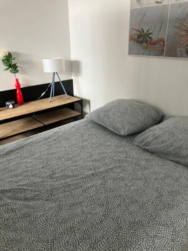 Un dormitorio con una cama y una mesa con una lámpara. en Le Petit Lecoy, en Saumur