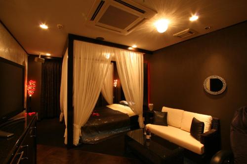 a bedroom with a bed and a couch and a mirror at Hotel Festa Qugiella -ホテル フェスタクジーラ- in Okayama