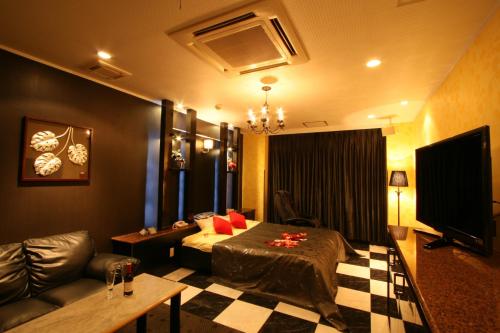 a room with a bed and a couch and a television at Hotel Festa Qugiella -ホテル フェスタクジーラ- in Okayama