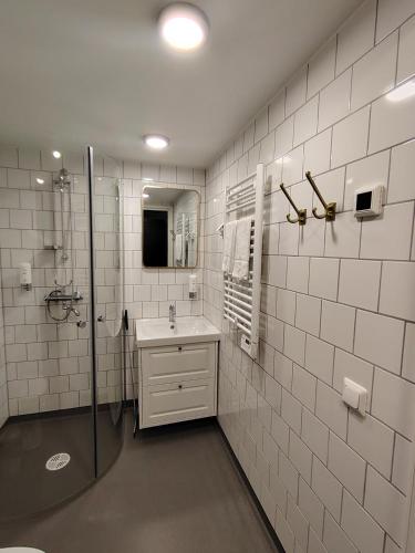 a white tiled bathroom with a shower and a sink at Juthbacka Hotell in Uusikaarlepyy