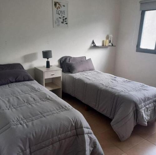 a bedroom with two beds and a table with a lamp at Casa del campo in Mar del Plata