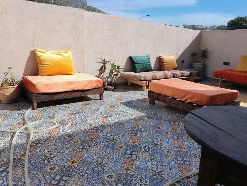 een patio met banken en tafels op een dak bij Water Dance in Imsouane