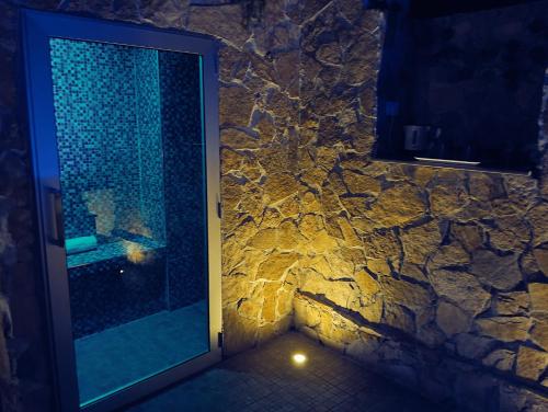 a bathroom with a glass door with a rock wall at SPA SUITE SICILIA - Intera casa con spa privata Jacuzzi Sauna Bagno di Vapore ad uso illimitato in Rosolini