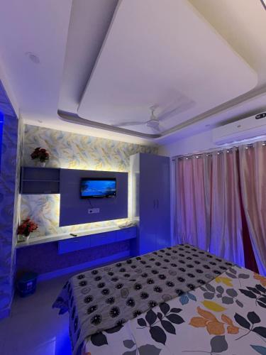 a bedroom with a bed and a tv on the wall at Happy Stay expo in in Greater Noida