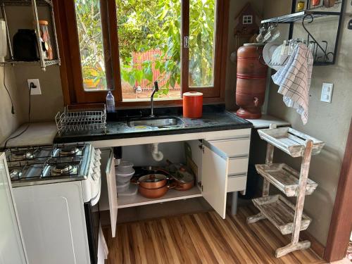 a kitchen with a sink and a stove and a window at Casinha da Mila in Piatã