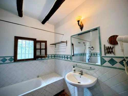 a bathroom with a sink and a tub and a mirror at Villa La Margarita Rocabella in El Chorro