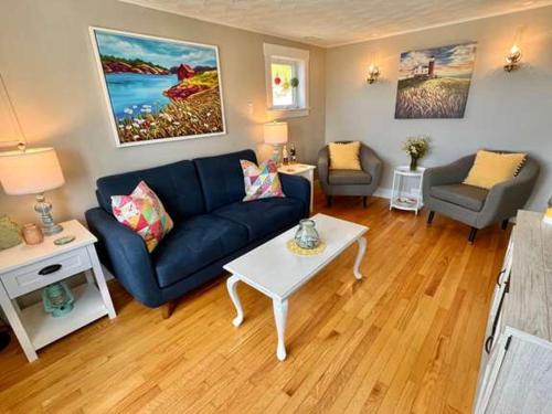 Una sala de estar con un sofá azul y una mesa. en Stockley's Saltbox, en Twillingate