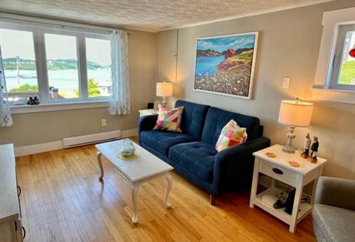 Una sala de estar con un sofá azul y una mesa. en Stockley's Saltbox, en Twillingate