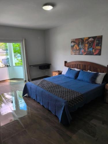 a bedroom with a bed with blue sheets and a window at Farol dos Coqueiros in Angra dos Reis