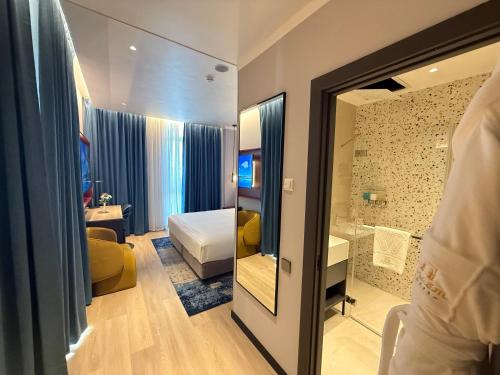 a bedroom with a bed and a bathroom with a mirror at Khorazm Hotel in New Uzbekistan Park in Teshabayguzar