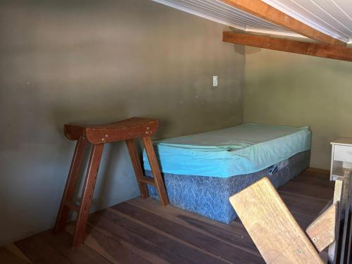 a small room with a bed and a stool at Casinha da Mila in Piatã