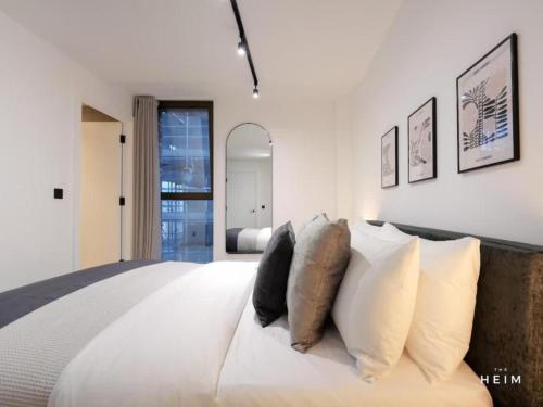 a bedroom with a large white bed with pillows at Pappilo at The Heim Residences in Manchester
