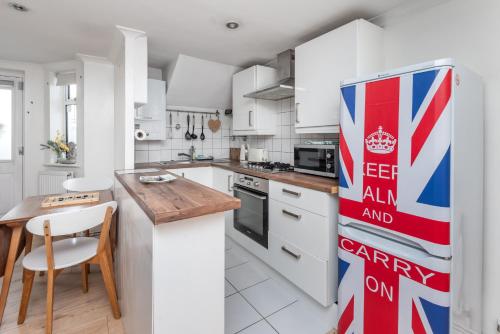 a kitchen with white cabinets and a refrigerator at Charming 1BD Flat with Garden Wimbledon Village in London