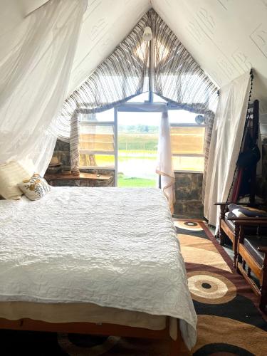a bedroom with a bed with a large window at TREE HOUSE Lodge in Gilgil