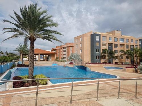 ein Pool mit einer Palme und einige Gebäude in der Unterkunft Bello Apartamento frente al mar in El Morto de Barcelona